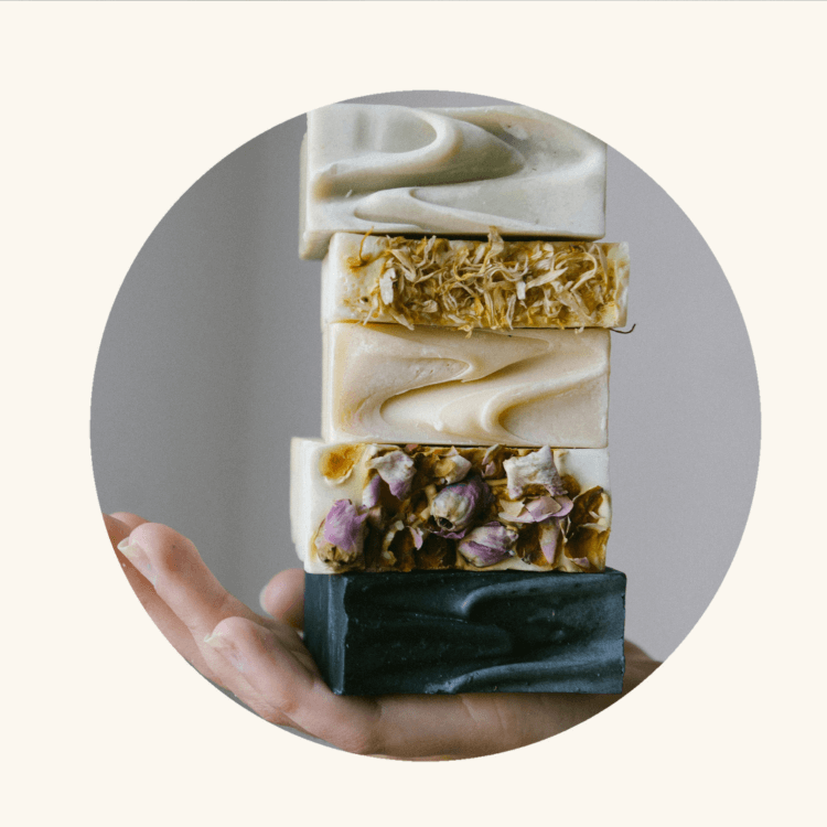 A hand holding a stack of five artisanal soap bars