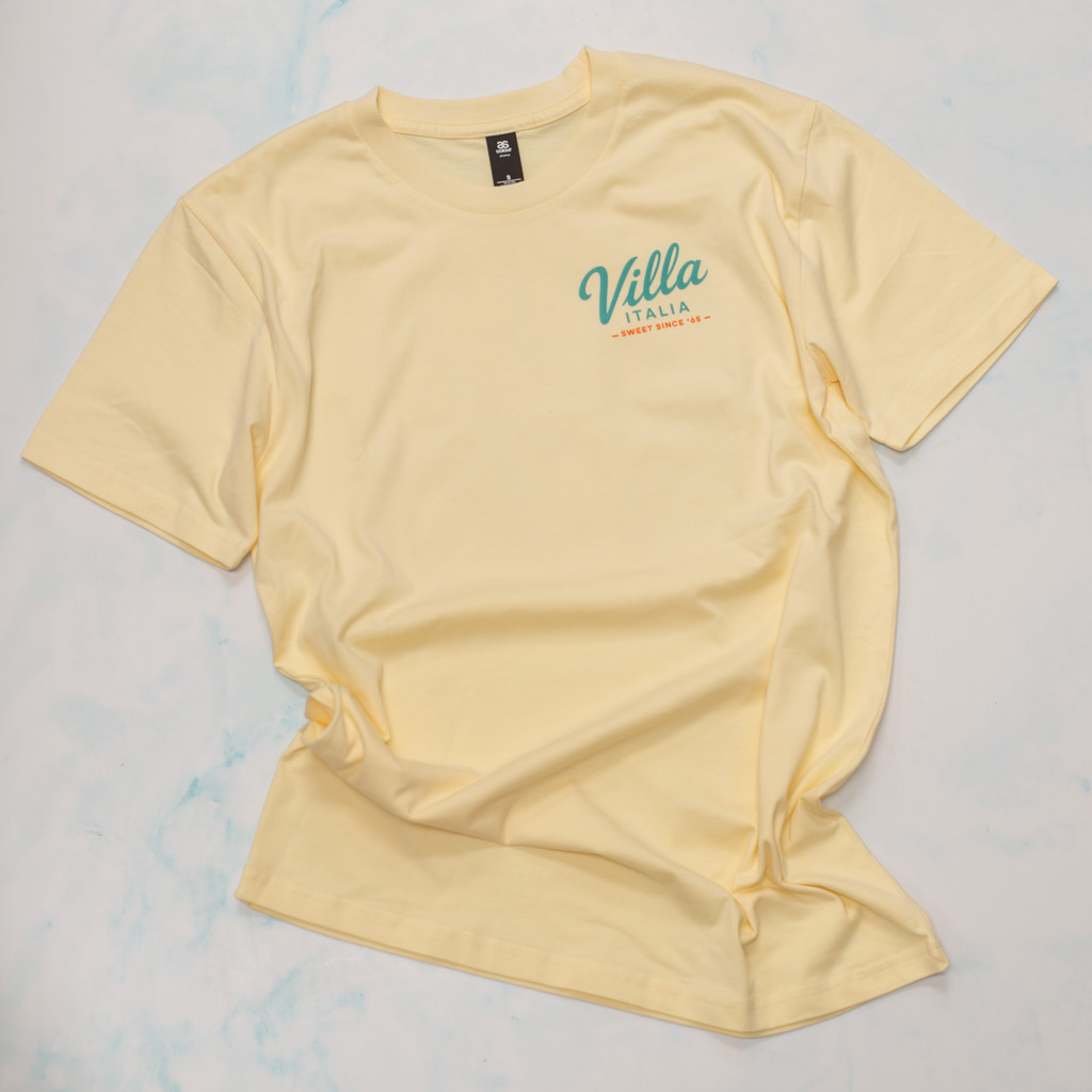 Bring home a piece of Villa Italia history with the exclusive Little Joe™ Collection T-Shirt. Made from the premium AS Colour 5001 Staple Tee, these 100% cotton shirts feature vintage-inspired Villa Italia artwork celebrating our Italian bakery heritage since 1965. Available in Butter, Pale Pink, and Seafoam, each design showcases Little Joe™ in classic Italian scenes, from cruising a vintage Fiat 500 to delivering sweet treats on a Vespa. Comfortable, durable, and perfect for Villa Italia fans, bakery lovers, and anyone who appreciates timeless Italian style. Shop the official Villa Italia Little Joe™ Collection today.
