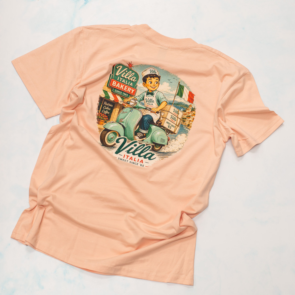 Bring home a piece of Villa Italia history with the exclusive Little Joe™ Collection T-Shirt. Made from the premium AS Colour 5001 Staple Tee, these 100% cotton shirts feature vintage-inspired Villa Italia artwork celebrating our Italian bakery heritage since 1965. Available in Butter, Pale Pink, and Seafoam, each design showcases Little Joe™ in classic Italian scenes, from cruising a vintage Fiat 500 to delivering sweet treats on a Vespa. Comfortable, durable, and perfect for Villa Italia fans, bakery lovers, and anyone who appreciates timeless Italian style. Shop the official Villa Italia Little Joe™ Collection today.
