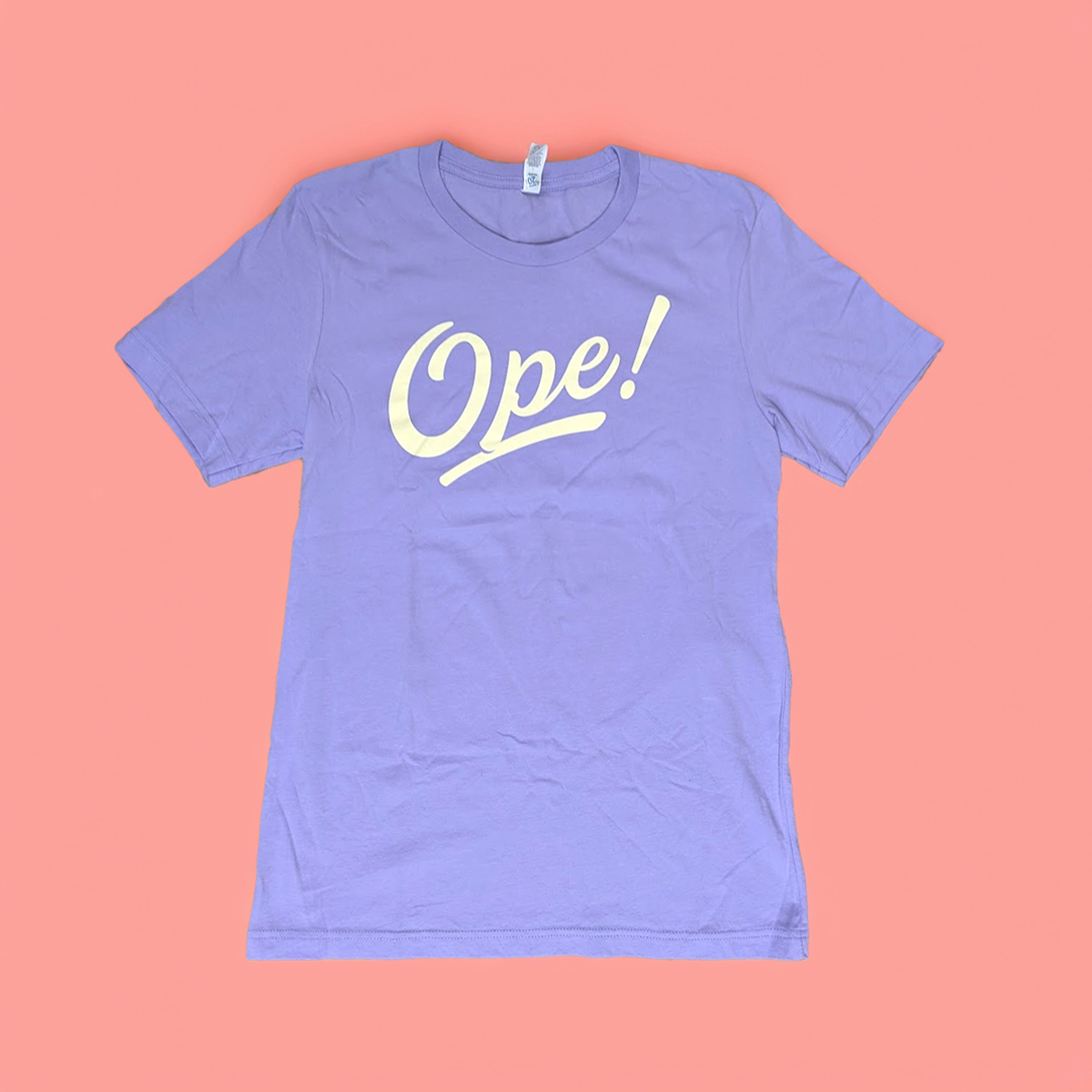 Lavender Ope! t-shirt against a coral backdrop
