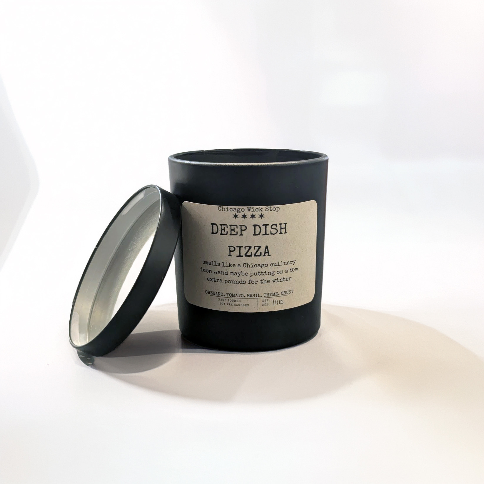 Chicago Wick Stop 10oz Deep Dish Pizza scented candle in a black jar with the lid off, showing the label with scent notes.