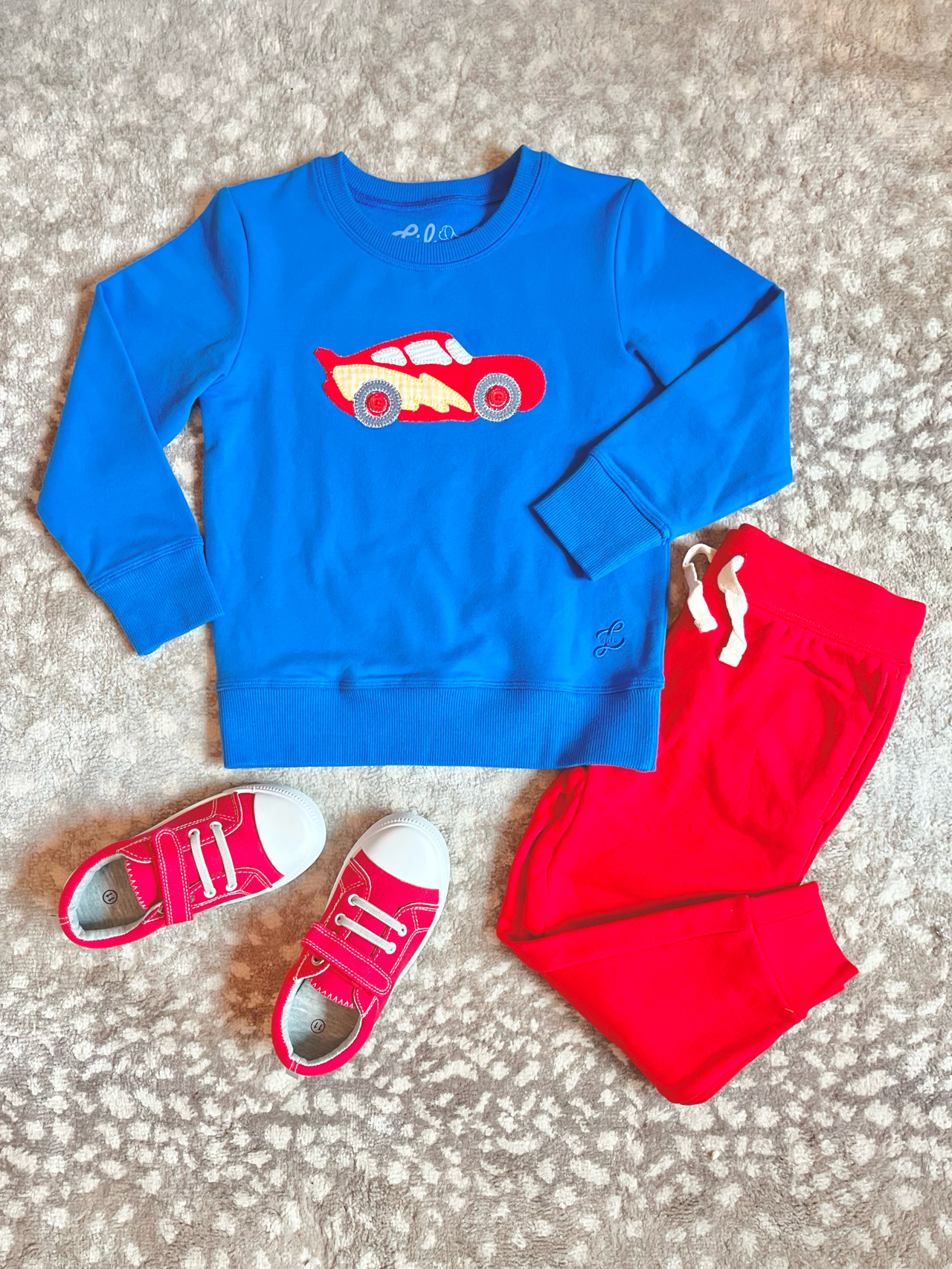 red applique race car on blue sweatshirt. shown with red pants and shoes for outfit inspiration.