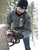 Man cutting a tree with a chainsaw in the snow, wearing Extreme sweater jacket