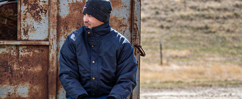 Man working outside in cold weather wears winter work jacket.