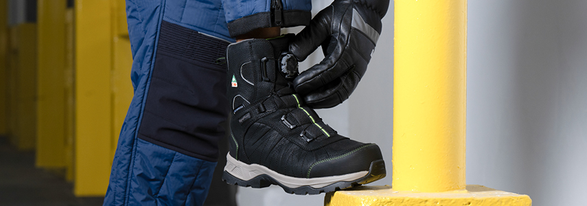 Man working in a cold storage warehouse adjusts the BOA Fit System on the Extreme Freezer Boot.