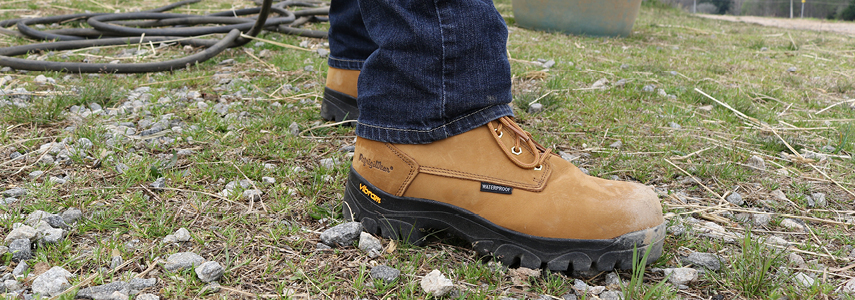 Man working outside in wet conditions wears a leather insulated work boot.