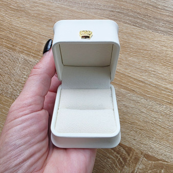 Gold crown embellishment on solid ring box with slightly off white Leatherette outer and soft inner to slip in your ring of choice for gifting. Dimmensions L580mm x H580mm x D680mm