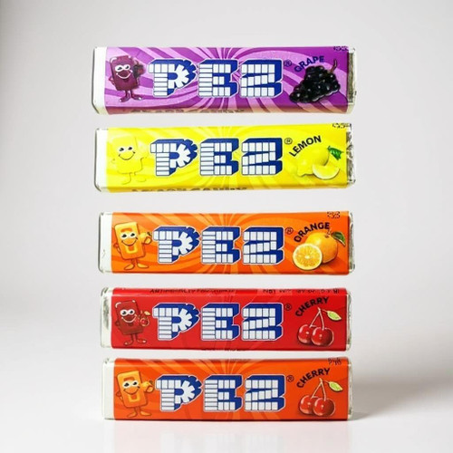 Assorted PEZ candy refill packs in multiple fruit flavors including lemon, grape, strawberry, orange, and cherry shown in original retail packaging.