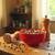 A red bowl of peppercorns on a wooden table beside a grinder, highlighting their perfect use for fresh-ground cooking.