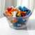 A clear plastic container filled with assorted bone-shaped candies, photographed indoors with soft lighting — shows freshness and variety.