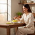 Woman enjoying banana candies at a cozy kitchen table — lifestyle image showing enjoyment.