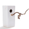 MENSCHMADE "Bird's Palace" ceramic bird house resembling a Tetra milk pack and a hazelnut twig as bird seat (front view)