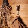A hand-carved Arabian Horse wall hook mounted on a wall, holding a heavy woven bag next to a vase of dried flowers.