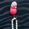 Three quater view of a hand-carved wooden Galah wall hook, featuring its iconic pink with a realistic hand-painted finish and  holding a necklace.