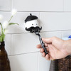 A hand puts a razor into the black and white 'Mr Razor' razor holder with a beret and oversized moustache.