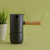 Minimalist Scandinavian stovetop espresso maker with wooden handle on a kitchen counter.
