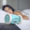 CLOCKY Aqua Blue Alarm Clock On Wheels jumping off the beside table, sleeping girl in the background