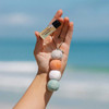 Smelly Balls diffuser Seapink hanging on hand with ocean in the background | the design gift shop