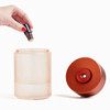 Somebody adding essential oil to the orange Lexon Horizon Aromatherapy Diffuser.