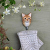 A hand-carved Ginger Cat wall hook mounted on a wall, holding knitwear against a grey background.