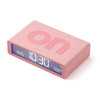 Angled view of the Lexon Flip Classic Pink digital alarm clock with the 'ON' text embossed on top.