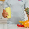 Lifestyle photo: lemon smoothie cup with fruit on bench.
