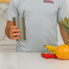 Lifestyle photo: smoothie cup in titanium with fruit on a bench top.

