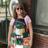 Smiling woman wearing the funny Blue Q Parsley, Sage, Rosemary and F*ck Off apron outdoors.