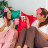 Two women enjoying hot drinks in festive pyjamas, holding the Annabel Trends Dachshund coffee mug next to a Christmas tree.