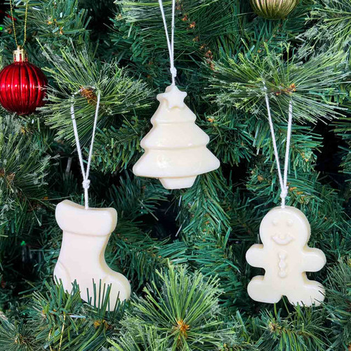 Christmas ornaments/candles (gingerbread man, stocking, tree) hanging on a green Christmas tree.