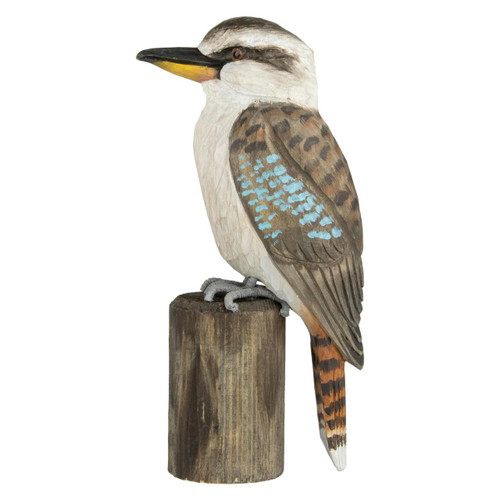 Side profile of a hand-carved Kookaburra DecoBird sculpture perched on a wooden post, showing its large beak and blue wing markings.