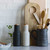 AUDO carbon and ash bottle grinders styled on kitchen bench with utensils and subway tiles.