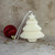 Soy wax Christmas tree shaped candle with a star topper next to a red ornament.