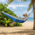 Blue hammock with grey upper hung between trees on the beach — person reading.
