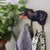 A close-up lifestyle shot of the Black Labrador wall hook mounted next to a Dachshund hook, with the Lab holding a decorative patterned bandana and the Dachshund holding a checkered tea towel.