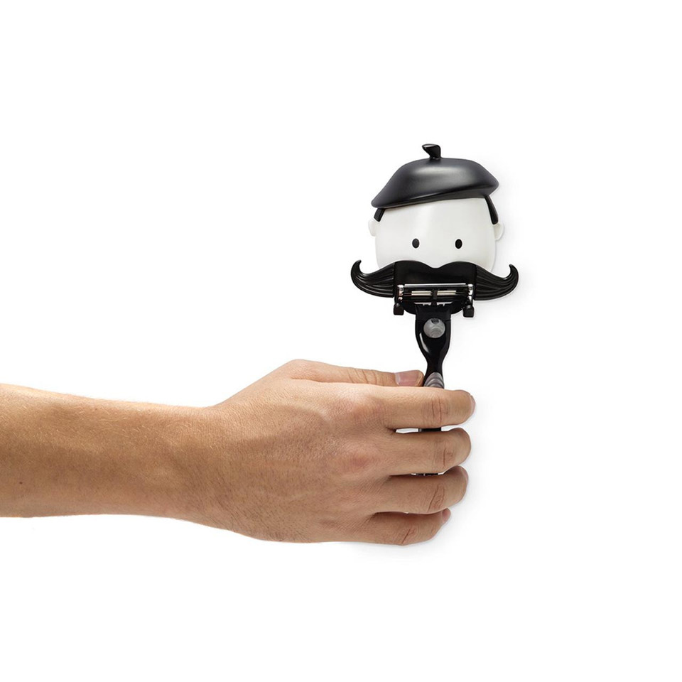 An outstretched hand holds the black and white 'Mr Razor' razor holder with a beret and oversized moustache.