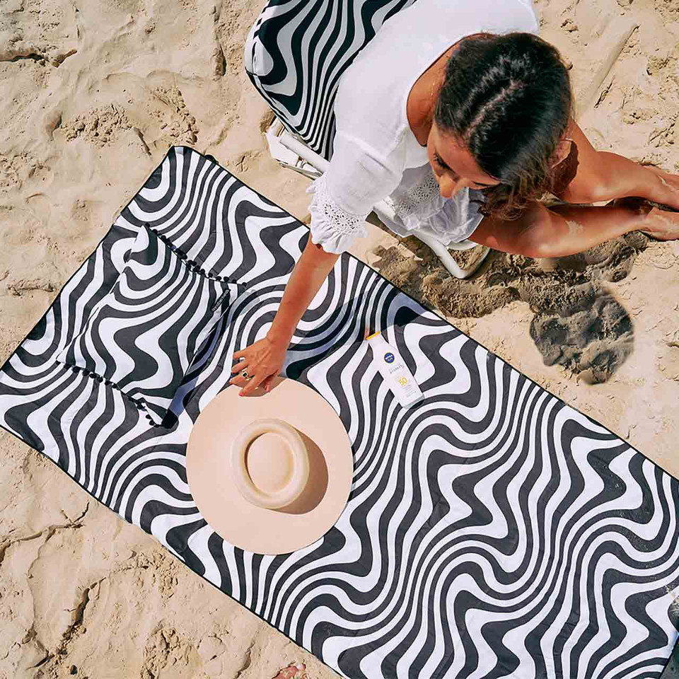 Arial view of sand-free beach towel Hypnotic Swirl at the beach with woman | the design gift shop