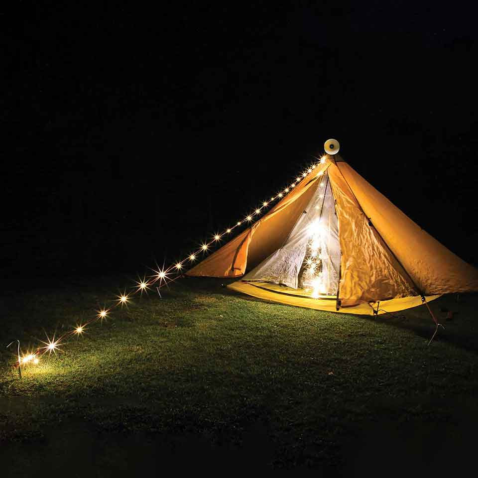 Warm-white retractable string lights decorating a tent at night.