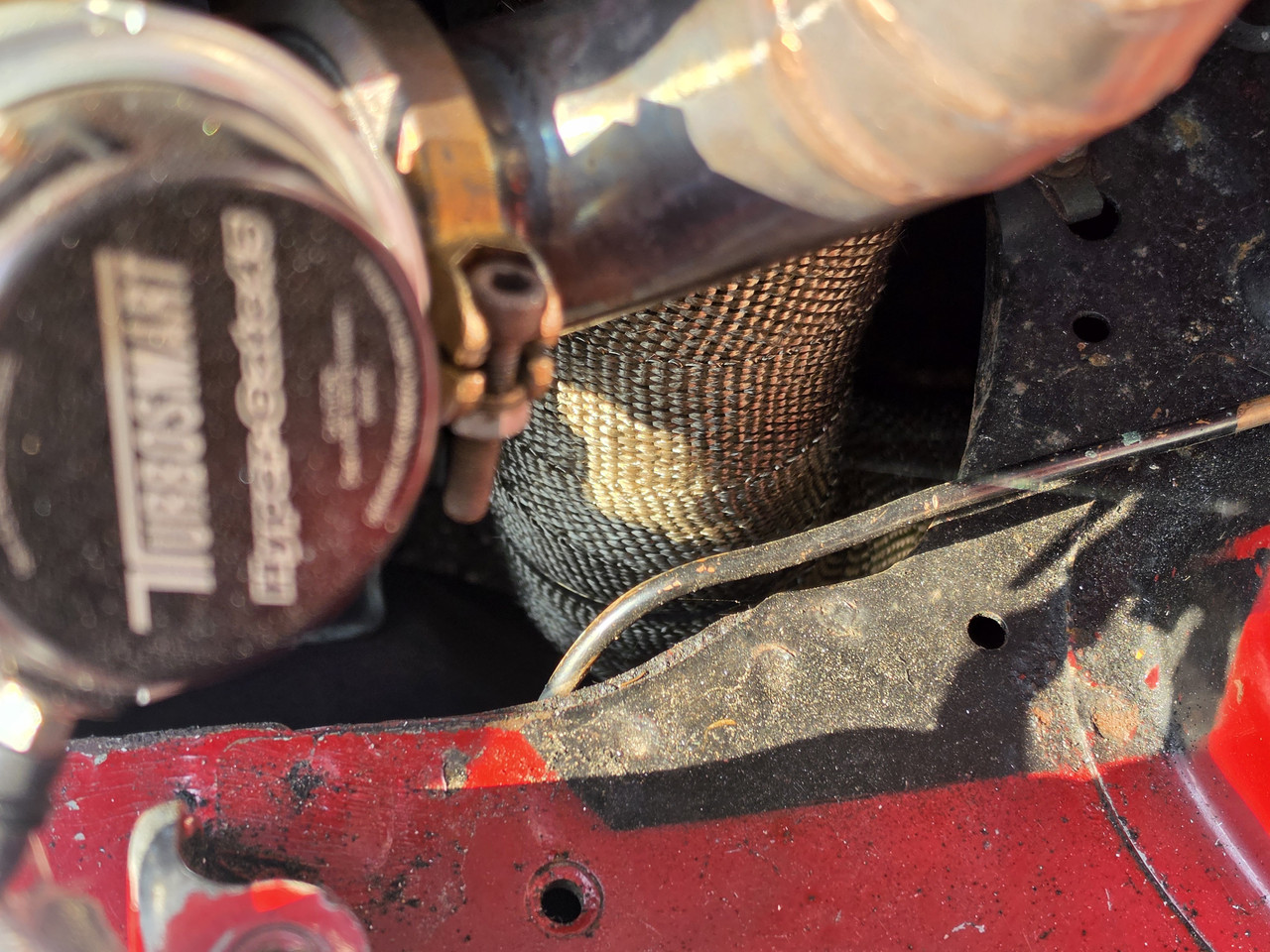 Close up of a turbo MX-5 brake line running close to a wrapped downpipe and turbo heat source