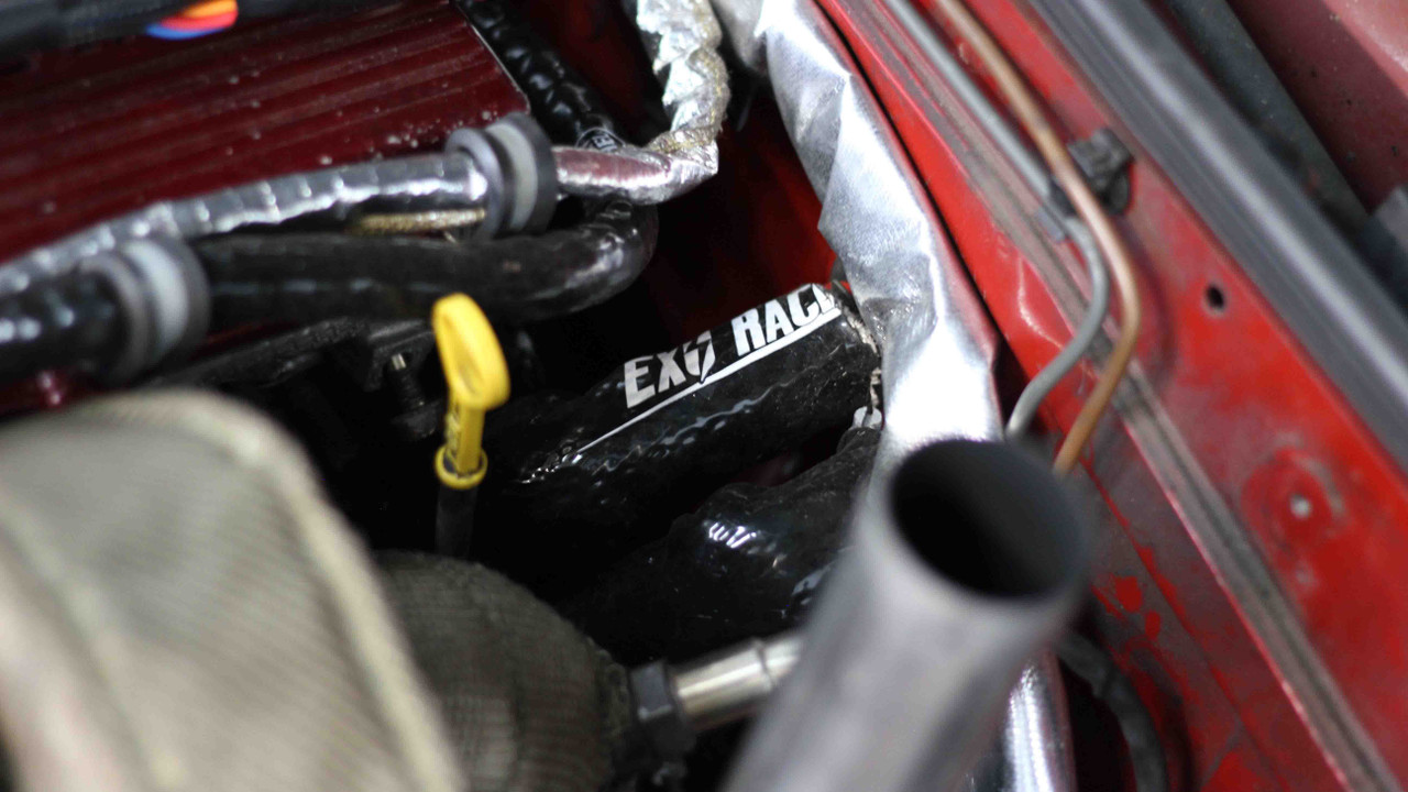 Close up of heat sleeve protecting a line in a turbo MX-5 engine bay near the bulkhead