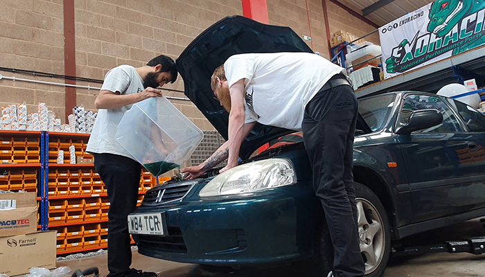 Fresh coolant being poured back into the radiator after silicone hose installation
