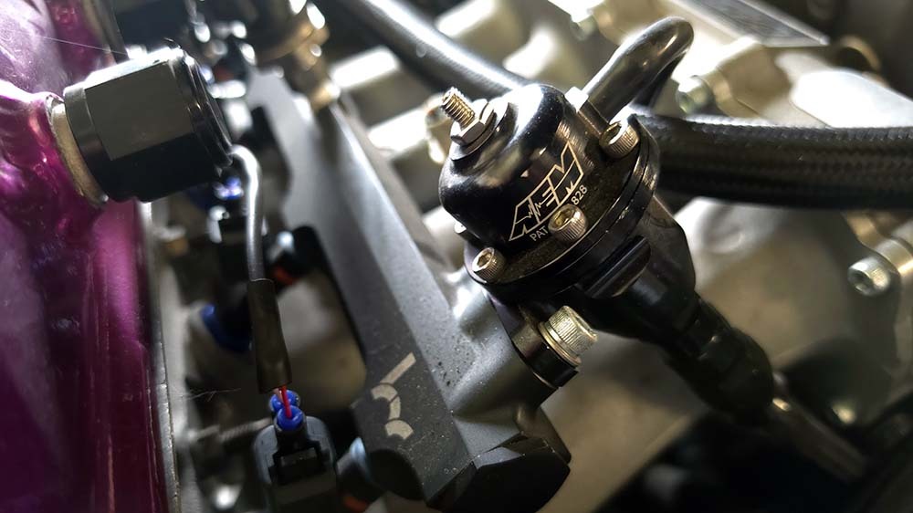 AEM fuel pressure regulator and fuel hose fittings in an engine bay