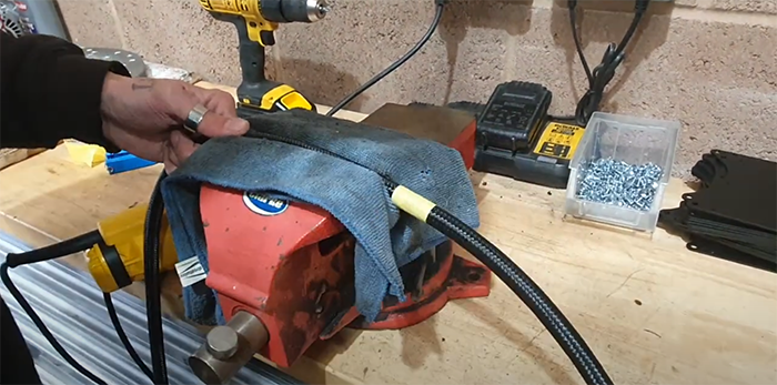 Braided PTFE hose held in a vice with the taped cut point overhanging