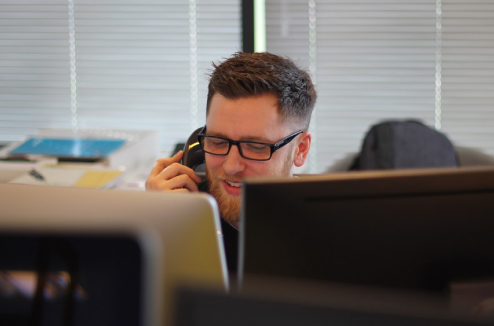 Technical support engineer taking a call. Man behind screens.