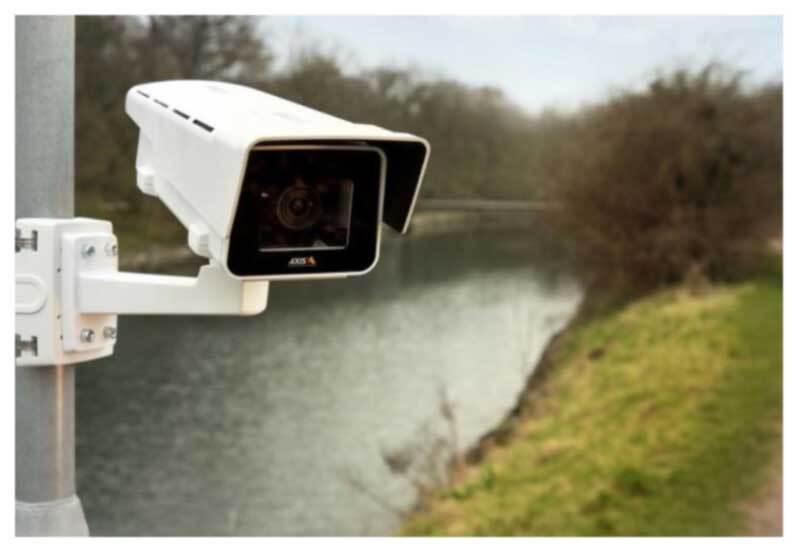 Camera mounted to pole by a river