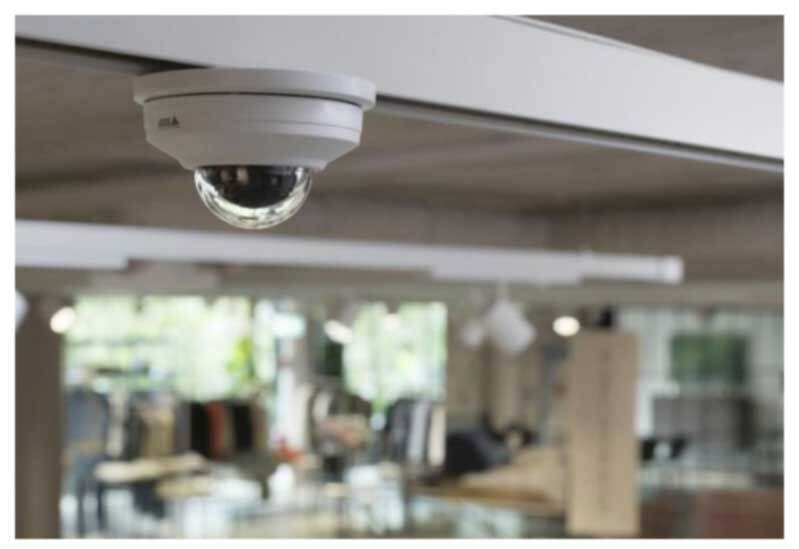 Camera mounted to ceiling in an office or retail space. The camera is in focus but the room is blurred.