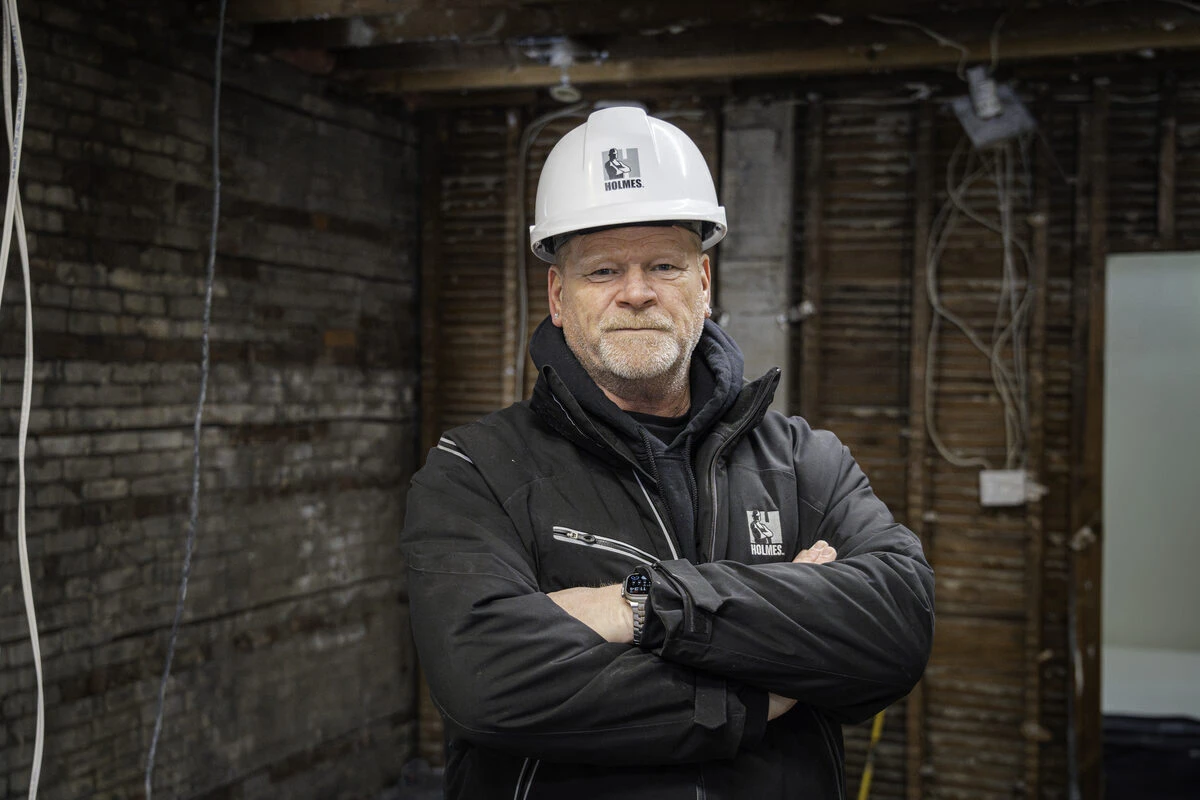 Mike Holmes portrait, arms crossed, on a job site