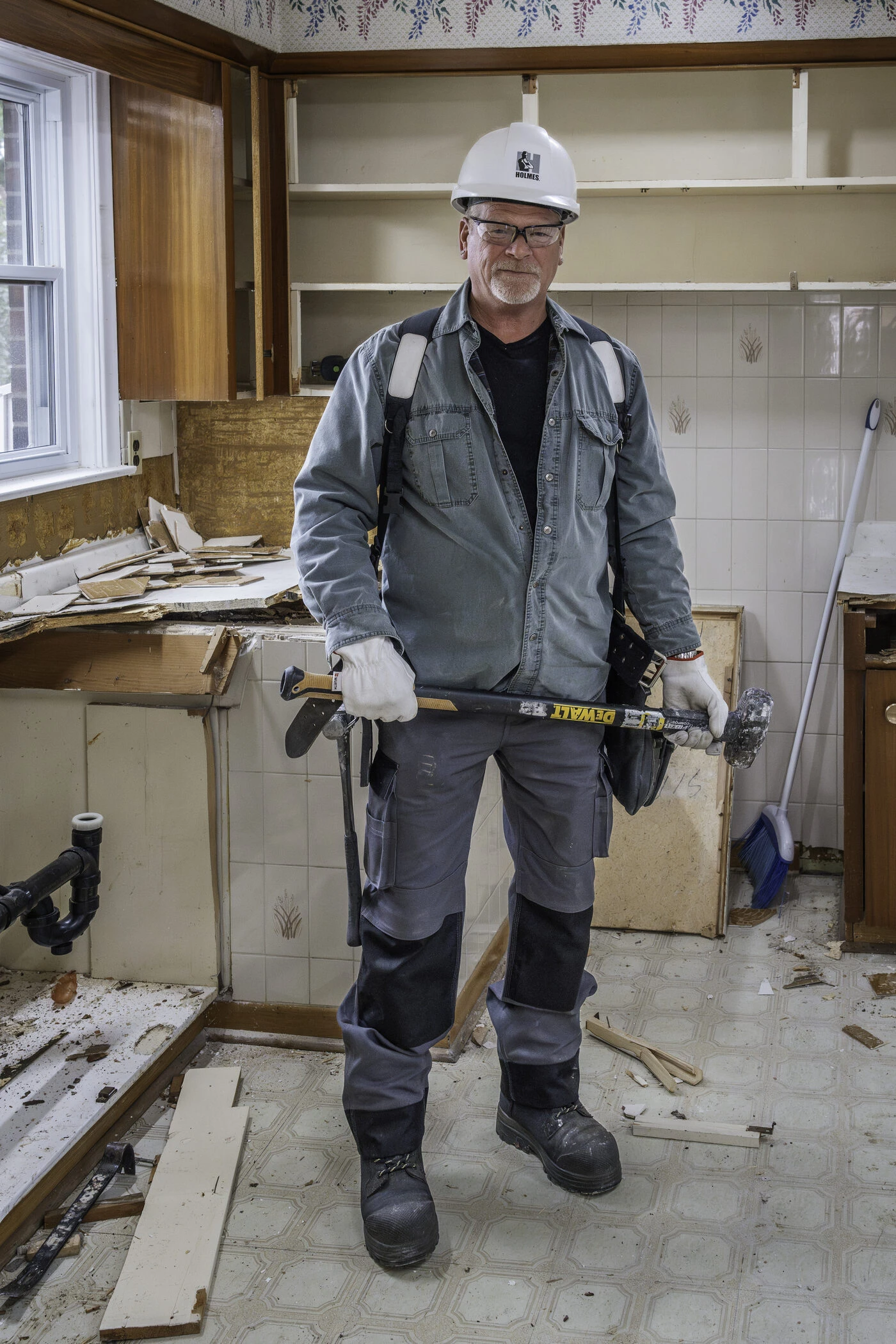 Mike Holmes holding a sledgehammer on a renovation job site