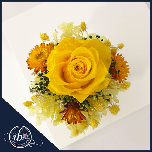 Golden Sunshine preserved mini flower arrangement featuring a vibrant yellow rose, orange daisies, yellow hydrangeas, and greenery in a sleek gold vase by Ritzy Blooms in Fort Lauderdale.