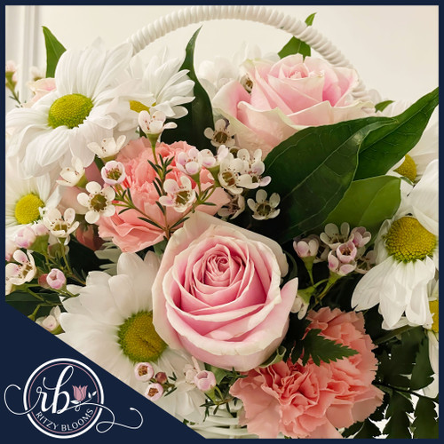 Blush Daisy Dreams Baby Girl Basket featuring soft pink roses, white daisies, wax flowers, and a satin ribbon in a white wicker basket by Ritzy Blooms.